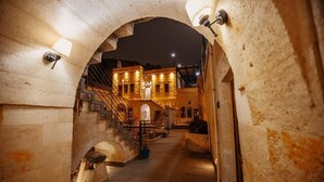 Un arco de piedra que da acceso a un edificio con escaleras y una puerta.
