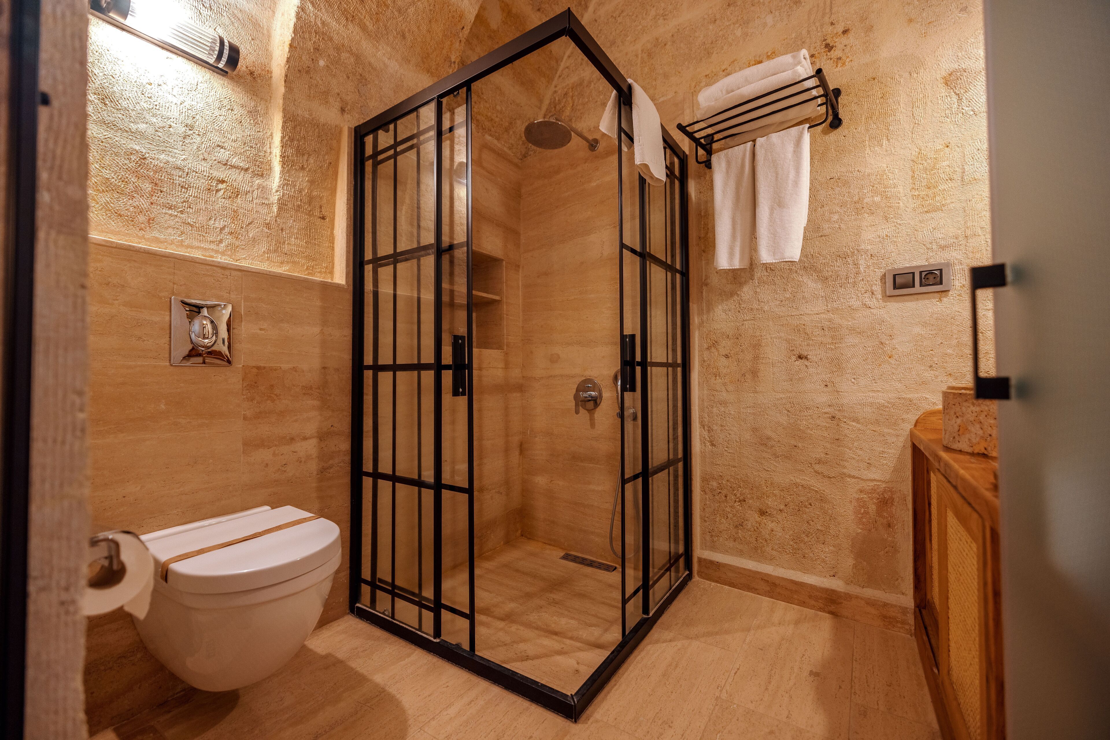 Un baño con ducha envuelta en vidrio, inodoro y tocador de madera.