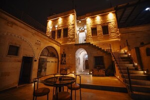 A historic building with a courtyard, stone walls, and a staircase leading to an upper level.