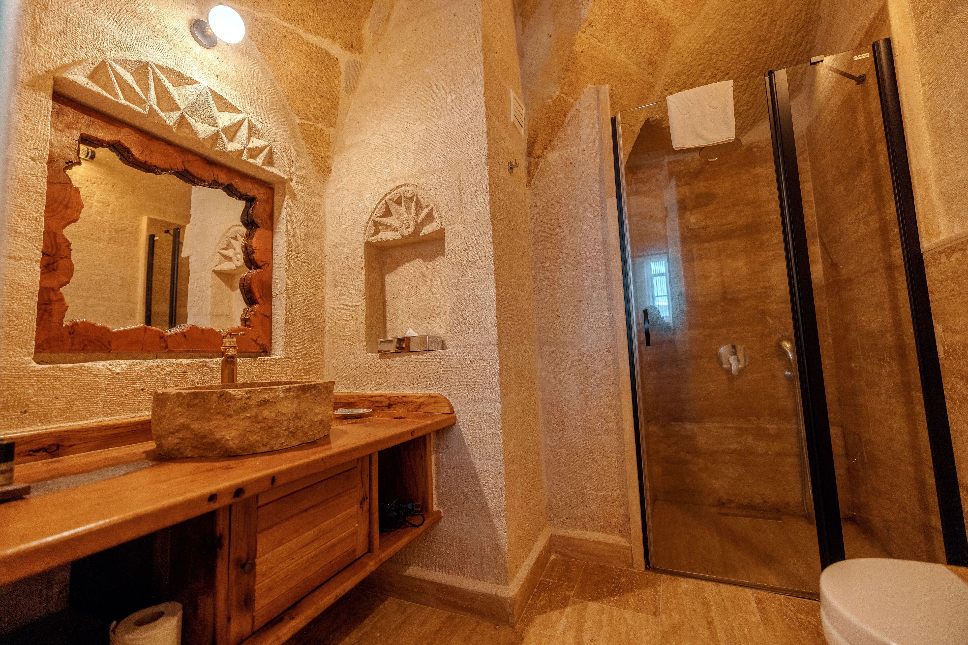 A bathroom with a stone sink, wooden vanity, and a glass shower enclosure.