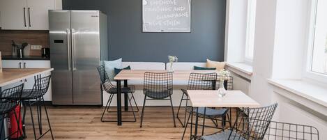 A modern kitchen with a stainless steel refrigerator, wooden flooring, and a chalkboard sign.