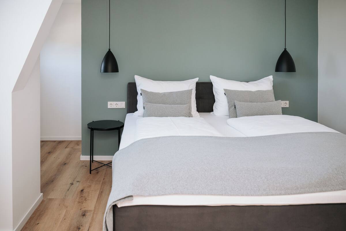 Un dormitorio con una cama, dos mesitas de noche y una pequeña mesa redonda.