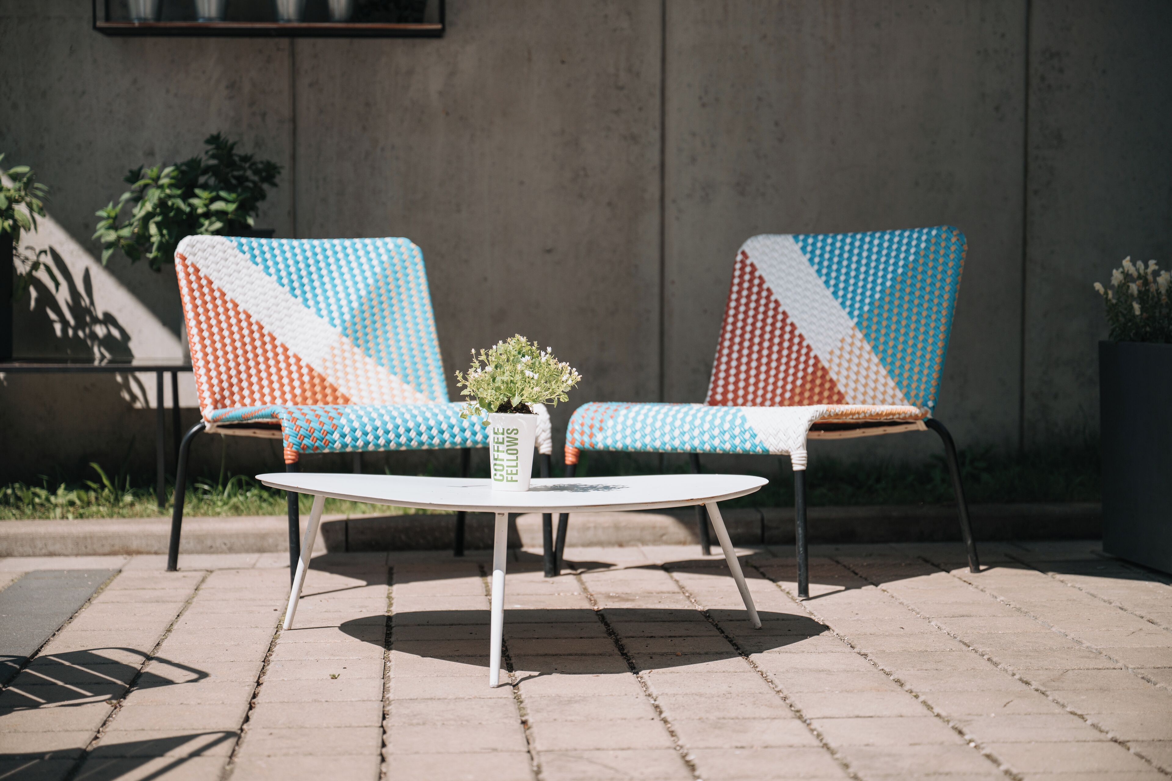 Two chairs with geometric patterns, a small table, and a potted plant with text on it.