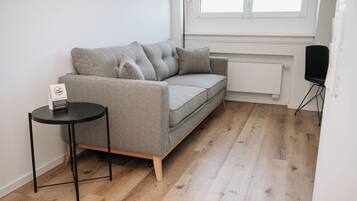 Una sala moderna con un sofá gris, una mesita auxiliar negra y una silla negra.