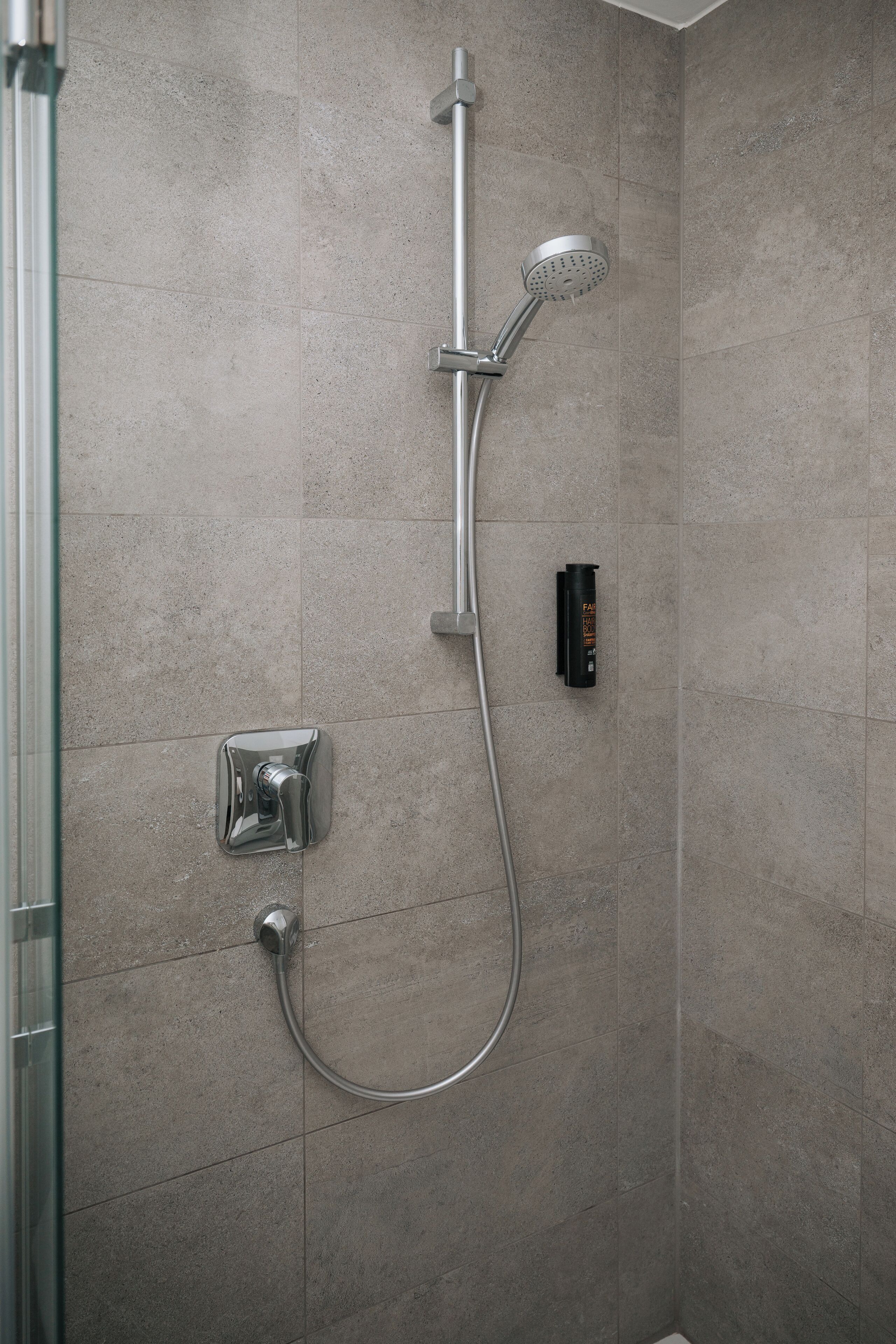 Ducha con cabezal de ducha manual y panel de control en la pared.