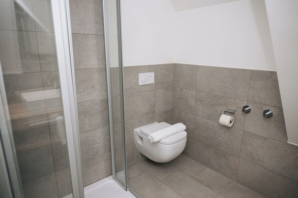 A modern bathroom with a glass shower enclosure, a toilet, and a towel rack. - Coffee Fellows Hotel & Longstay (Pfaffenhofen an der Ilm)