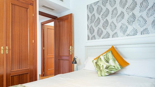A hotel room with a bed, a nightstand, a lamp, and a wardrobe.
