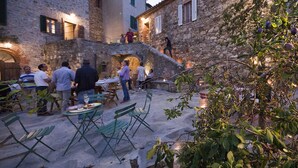 An outdoor dining area with stone buildings, tables, and chairs. - Agriturismo La Via dell'Oliviera (Chiusdino)
