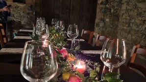 A table set with wine glasses, candles, and a centerpiece of fruits and greenery. - Agriturismo La Via dell'Oliviera (Chiusdino)