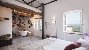 A bedroom with a large bed, a view of the countryside, a bathtub, and a wooden ceiling. - Agriturismo La Via dell'Oliviera (Chiusdino)