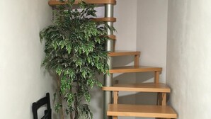 Una escalera en espiral de madera con una planta en maceta a su lado.