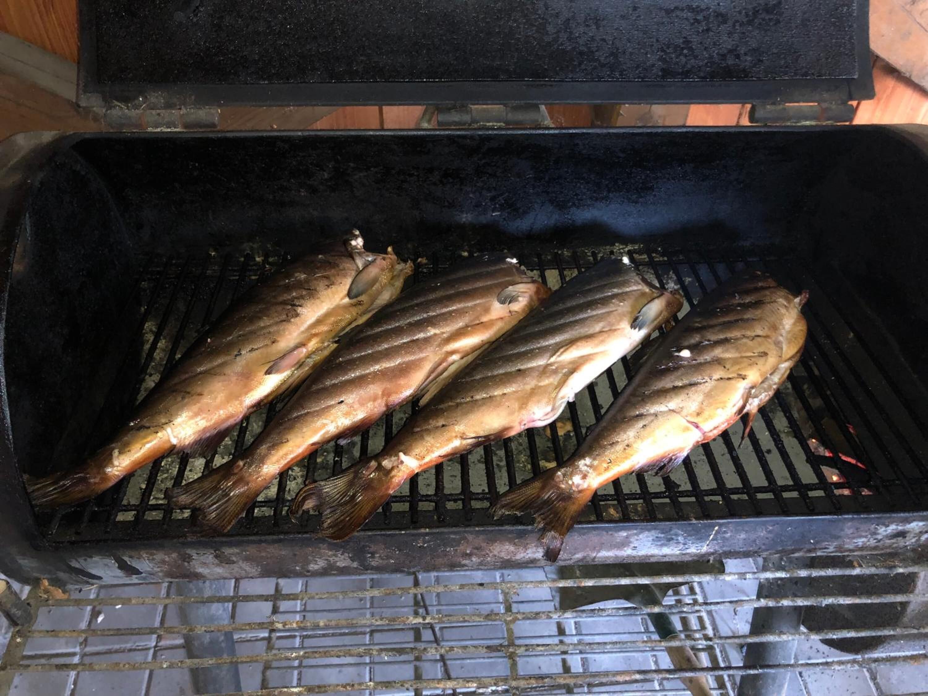 Three fish being grilled on a grill.