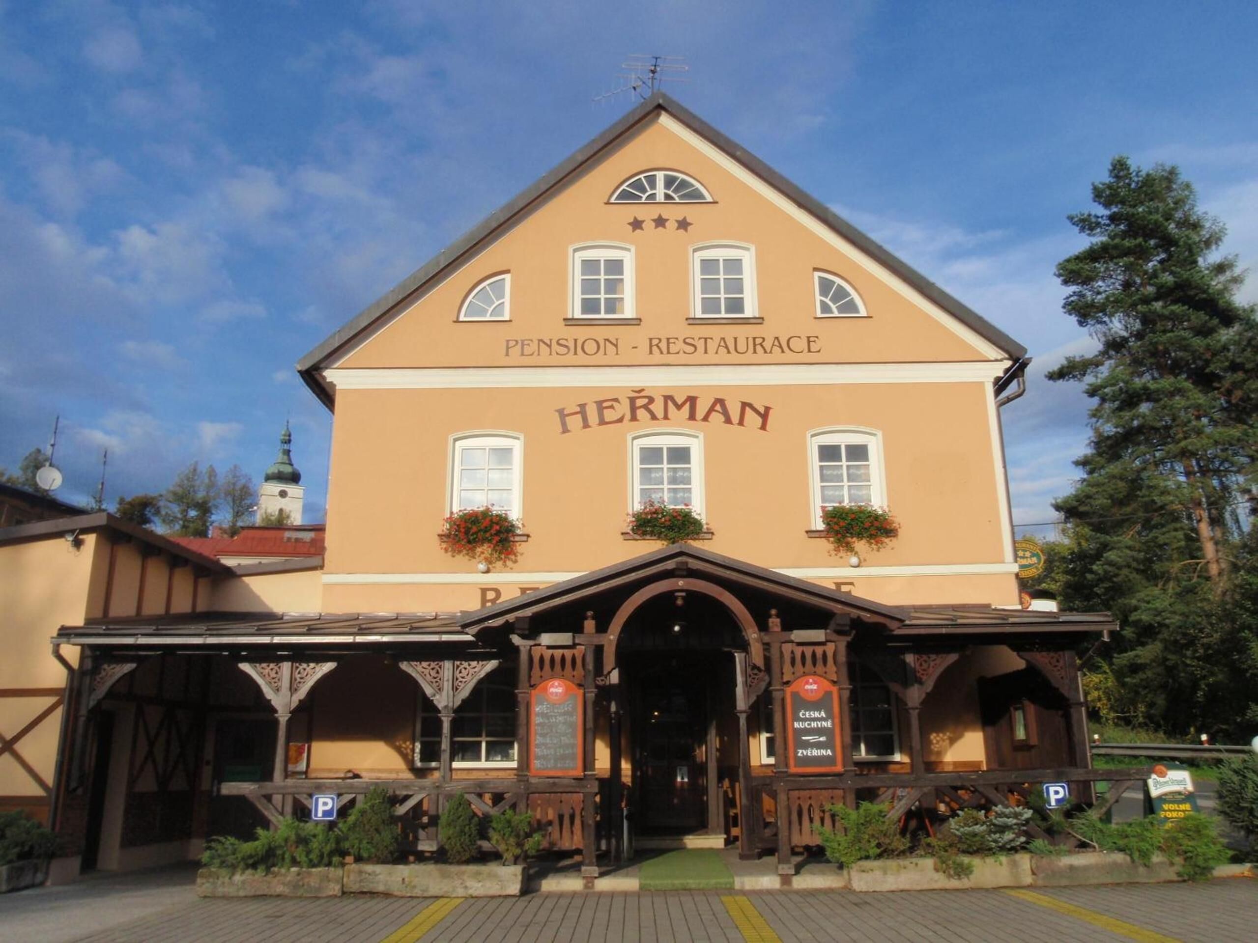 A two-story building with a sign reading "HERMAN Pension - Restaurant" and "ČESKÁ KUCHYNĚ ZYBĚRINA."