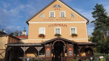 A two-story building with a sign reading "HERMAN Pension - Restaurant" and "ČESKÁ KUCHYNĚ ZYBĚRINA."