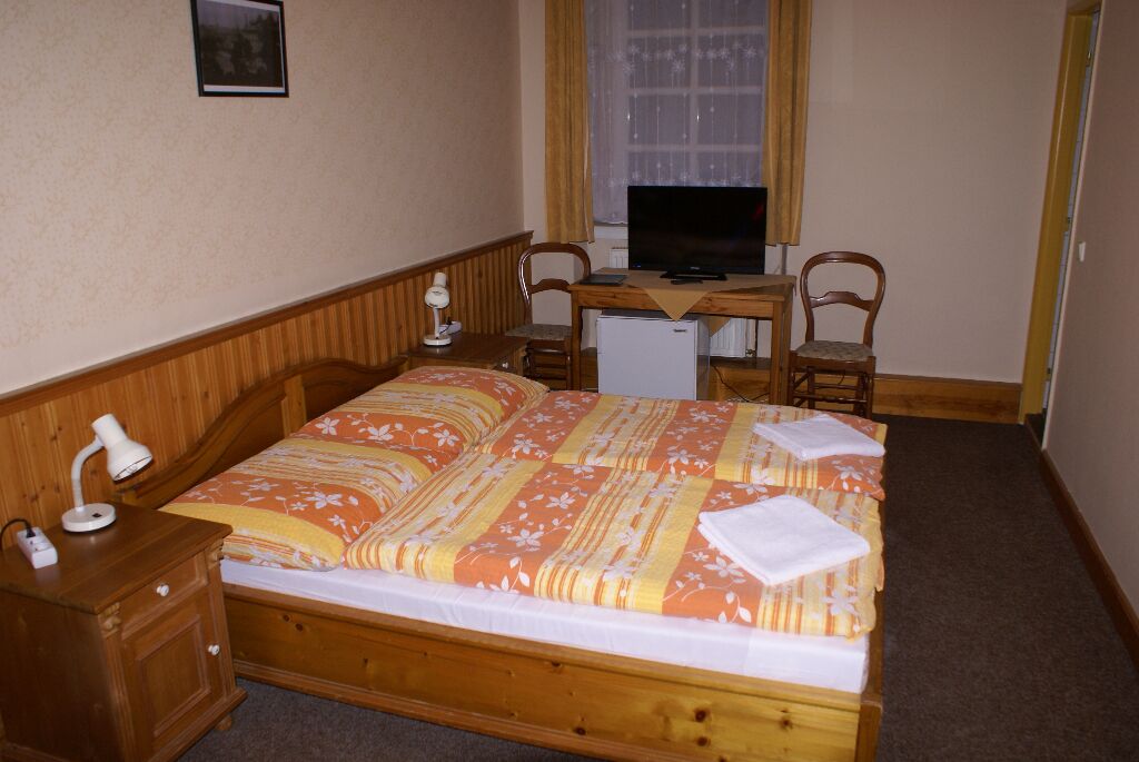 Een slaapkamer met een bed, een bureau, twee stoelen, een lamp en een televisie.