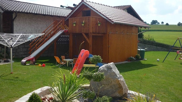 Una cabaña de madera con un tobogán y un columpio en el jardín.