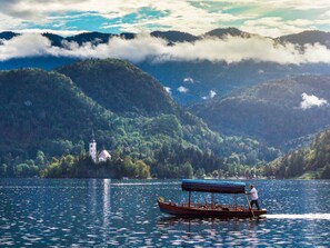 Enjoy serene lake views and a traditional boat, surrounded by lush hills and a historic church.