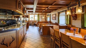 Un restaurante acogedor con interiores de madera, una zona de bar y diferentes disposiciones de asientos.
