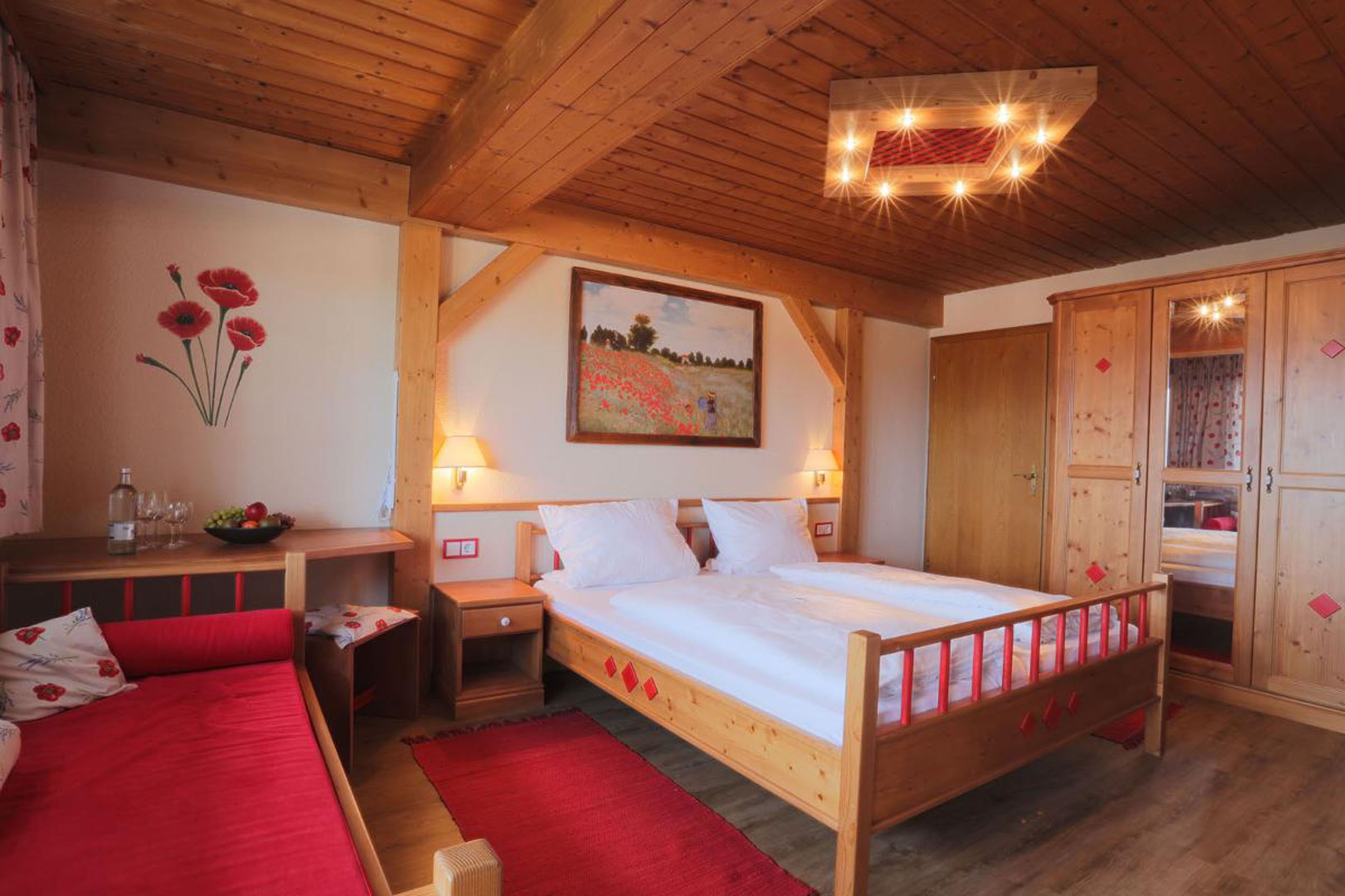 Une chambre à coucher en bois avec un lit simple, une table de chevet, un tapis rouge et un tableau accroché au mur.