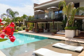 A modern poolside area with a clear pool, lounge chairs, and potted plants. - Flora Luxury Villa (Depressa)