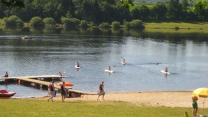 A lakeside scene with people kayaking and swimming. - Ferienwohnung Bücherl (Waldmuenchen)
