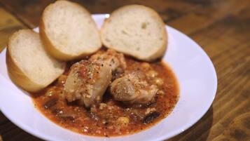 A plate of chicken with sauce and bread on a wooden table.