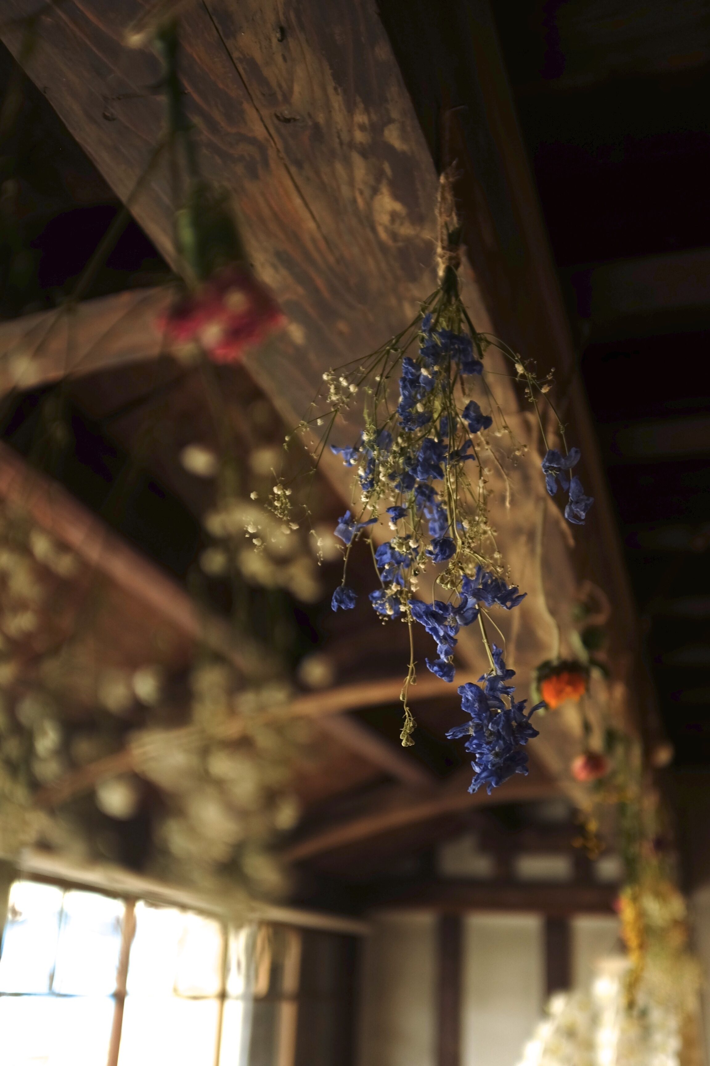 Un interior rústico con vigas de madera y arreglos florales colgantes.