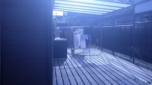 A wooden deck with a clothesline and a hanging chair.