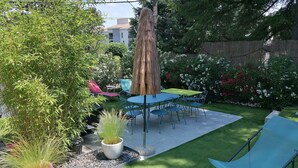 A patio area with a table and chairs, surrounded by greenery and a small garden.