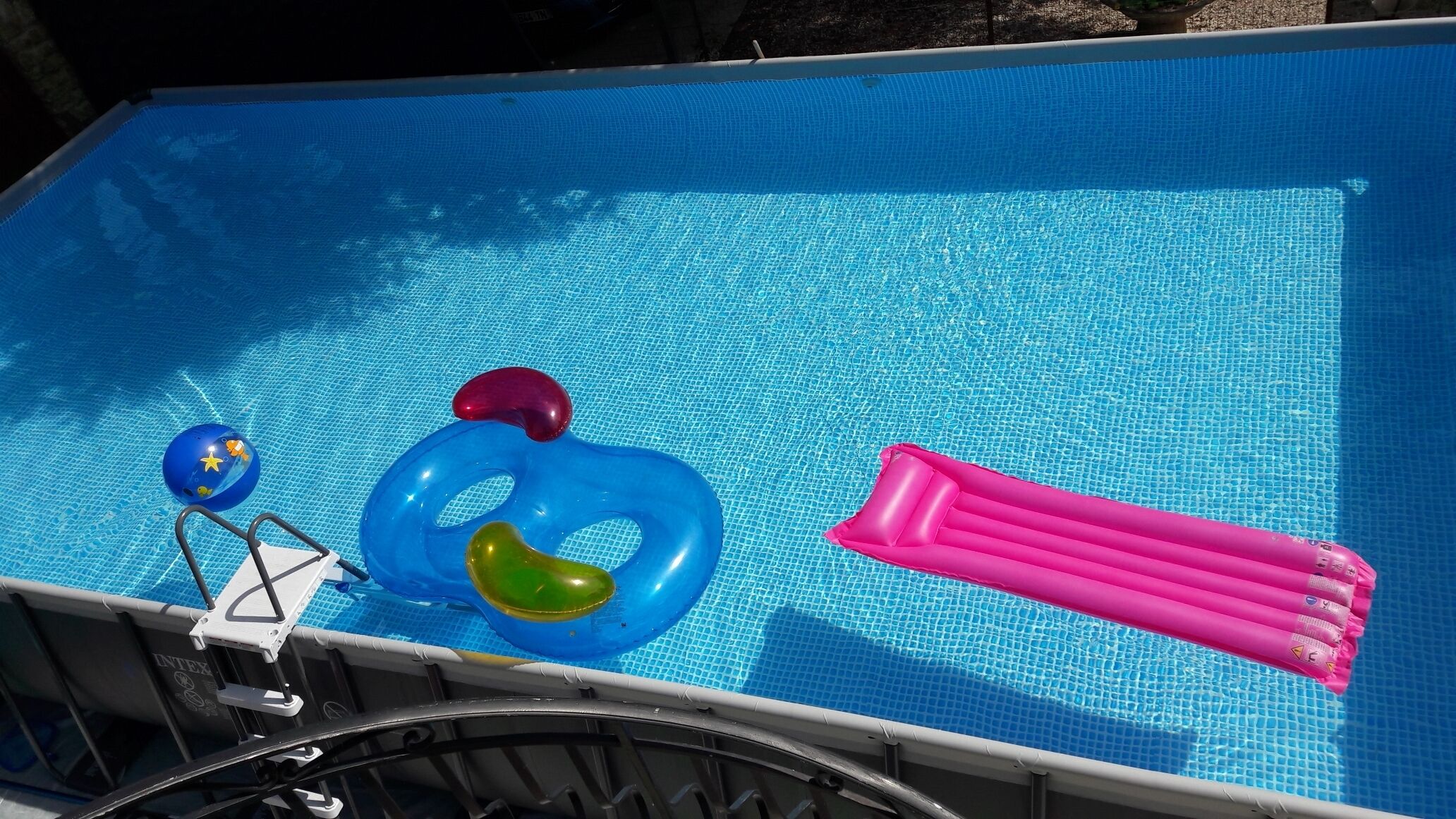 Una piscina con juguetes inflables y una escalera.