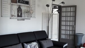A modern living room with a black sofa, a glass coffee table, and a white cabinet.
