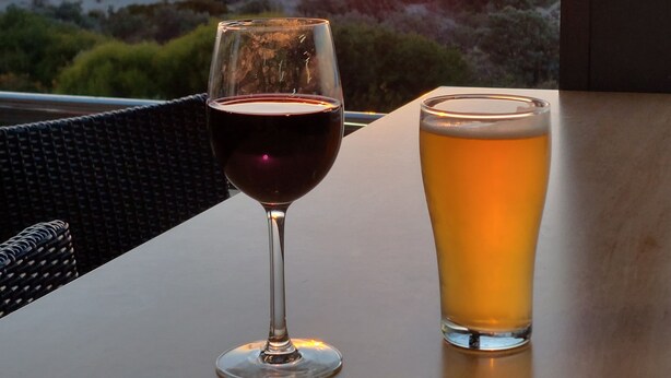 A table with two glasses of beverages, one red and one yellow, with a sunset view in the background. - Semaphore Sea Breeze-Family Beach/Pool Holiday. 450m to Beach. 20 min to airport (Semaphore)