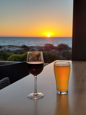 A table with two glasses of beverages, one red and one yellow, with a sunset view in the background. - Semaphore Sea Breeze-Family Beach/Pool Holiday. 450m to Beach. 20 min to airport (Semaphore)