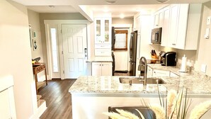 A modern kitchen with white cabinets, a granite countertop, and a stainless steel sink. - Coligny Beach- spacious 3 bed condo super clean and close to everything Coligny! (Hilton Head)