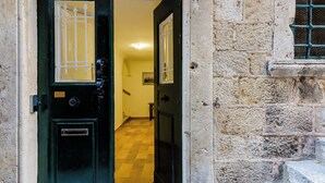 A narrow hallway with a green door and a stone wall. - Old city top spot apartments just one step from the main street Stradun (Dubrovnik)
