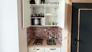 A compact kitchen with a microwave, stove, sink, and storage cabinets.