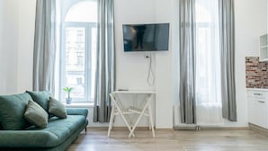 A living room with a green sofa, a TV mounted on the wall, and a small table.