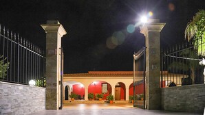 Una entrada protegida por una reja a un edificio con fachada roja y ventanas de arco.