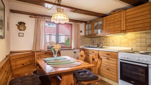 A kitchen with wooden cabinets, a stove, and a dining table with chairs. - Apartment 'Achraintal 1' with Mountain View and Wi-Fi (Lindau)