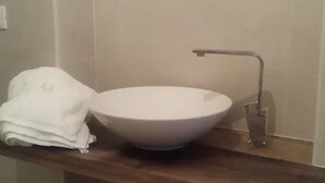 A bathroom with a white sink, a towel, and a wooden countertop.