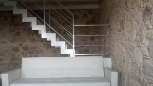 A white sofa in a room with a stone wall and a staircase.