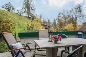 Une terrasse extérieure avec une table, des chaises et un vase à fleurs.