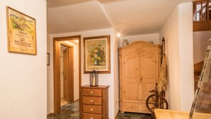 A hallway with a wooden wardrobe, a wooden dresser, a framed picture, and a bicycle.