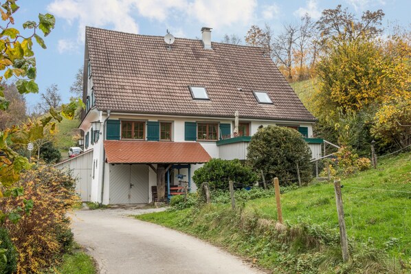 Une maison à deux étages, dotée d’un toit en pente, d’un porche couvert et d’un petit jardin.