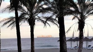 Una spiaggia con palme e una nave all'orizzonte.