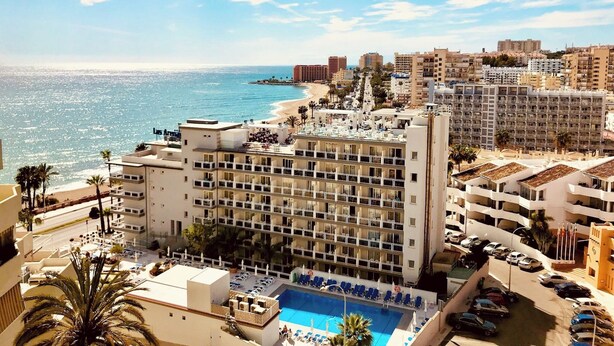 Un hotel con piscina, vista sulla spiaggia e diversi piani.