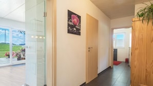 A modern interior with a glass door leading to a balcony, a wooden door, and a framed picture on the wall. - Holiday Apartment "Buche" with Wi-Fi, Mountain View, Terrace & Garden (Neukirch)