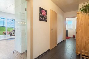 Un intérieur moderne avec une porte vitrée donnant sur un balcon, une porte en bois et un tableau encadré au mur.