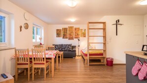 Une pièce chaleureuse avec une table à manger en bois, des chaises, un canapé, un lit superposé et une petite kitchenette.