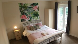 Ein Schlafzimmer mit einem Bett, einem Nachttisch und einem großen Fenster.